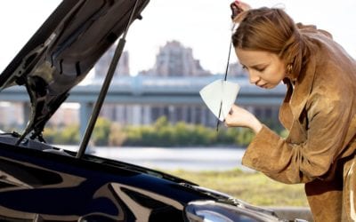 young woman inspecting a car and checking the oil